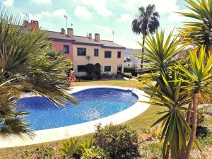 a swimming pool in front of a house with palm trees at Casa Tranquila La Duquesa in Manilva