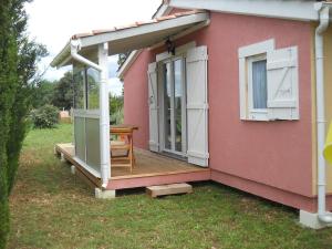 a pink house with a porch and a wooden deck at chalet nature 2 in Aspiran