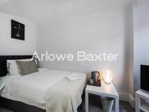 a bedroom with a bed and a table and a tv at Hackney Guest Rooms in London