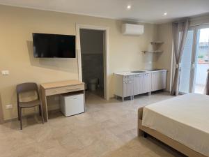 a bedroom with a bed and a desk and a television at Sofia s Rooms in Falcone