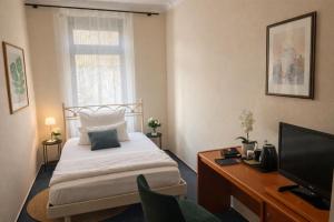 a bedroom with a bed and a desk and a television at Gästehaus Bock in Lahnstein