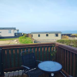 a chair and a table on a balcony at Our Retreat By The Waves in Bangor