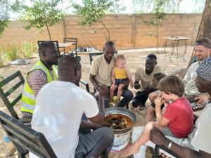 a group of people sitting around a table eating food at Lompoul Nature in Tioukougne Peul