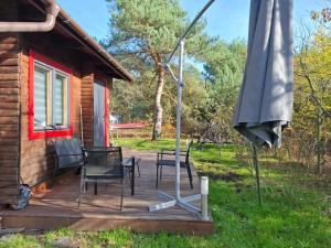 a deck with chairs and an umbrella next to a cabin at Domek w ogrodzie "Bzyczek" in Ostry Bór