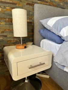 a nightstand with a lamp on it next to a bed at Petit Luxe in Mortroux