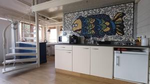a kitchen with white cabinets and a fish on the wall at Artistiek Vakantiehuisje in Hulst +21 photos