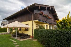 a yellow house with an umbrella and a bench at Penzion U Kuboňů in Volary