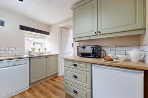 a kitchen with white cabinets and a counter top at The Barn Timberscombe in Timberscombe