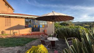 a table and chairs with an umbrella in front of a house at Antara House in Guasca +9 photos
