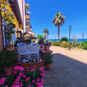 a bench on a sidewalk next to a building with flowers at La Mya Aurora in Finale