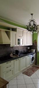 a kitchen with white cabinets and a chandelier at La Casetta di Mari in Legnano +22 photos