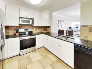 a kitchen with white cabinets and a sink at Brass Rail 310 in Tybee Island