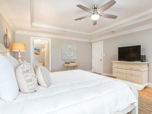 a white bedroom with a white bed and a flat screen tv at Brass Rail 310 in Tybee Island +26 photos