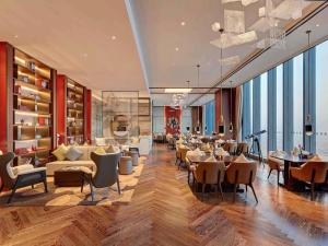 a hotel lobby with tables and chairs and windows at Pullman Huizhou Kaisa in Huizhou