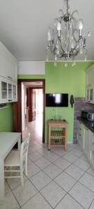 a kitchen with green walls and a table and a chandelier at La Casetta di Mari in Legnano