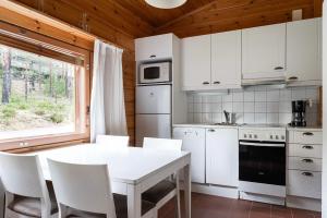 a kitchen with white cabinets and a table and chairs at Mökki Vierumäki in Myllykylä +22 photos