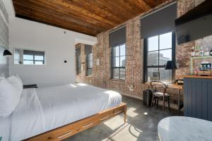 a bedroom with a bed and a desk and windows at Wythe Hotel in Brooklyn