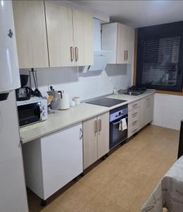 a kitchen with white cabinets and a stove top oven at Casa de sney in Sarria +21 photos