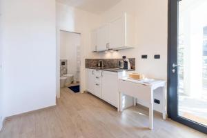 a white kitchen with a sink and a counter at Gli Oleandri in Bellano