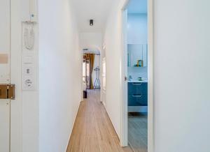 a hallway with white walls and a blue bathroom at The Art Flat in Figueres