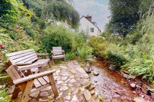 two wooden benches sitting next to a stream at High Bank Porlock in Porlock