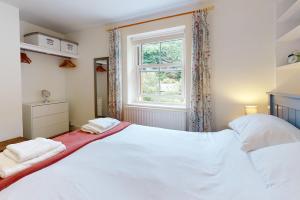 a bedroom with a large white bed and a window at High Bank Porlock in Porlock