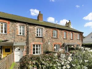 an old brick house with white windows and flowers at Grace Cottage Porlock in Porlock