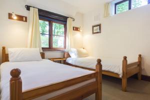 two beds in a room with two windows at The Smithy nr Huntsham in Tiverton