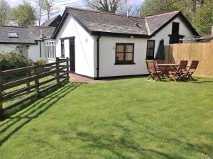 a white house with a table and chairs in a yard at The Smithy nr Huntsham in Tiverton