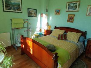 a bedroom with a wooden bed with a green comforter at Chambres d'hôtes Chez nous in Nantheuil