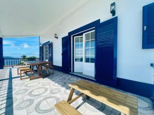 a patio with a wooden bench and a table at Island View Retreat in Feteira