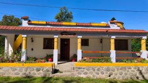 a house with yellow columns and flowers in front of it at Hostería La Pergola in Villa Serranita