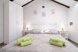 a white bedroom with a bed with two green pillows at Canary House in Ingenio