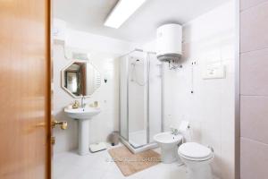 a white bathroom with a toilet and a sink at Room with kitchen & free parking 100 m from the sea in Quartu Sant'Elena +42 photos