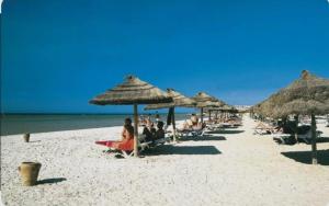 a group of people sitting under umbrellas on a beach at Primavera Marmara Hamam sousse in Hammam Sousse