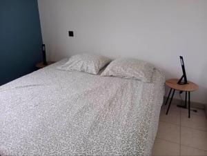 a bedroom with a bed with a white blanket and a table at Maison de vacances avec piscine in Soustons
