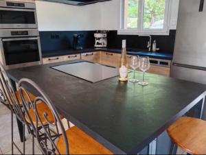 a kitchen with a black counter top with two wine glasses at Maison de vacances avec piscine in Soustons