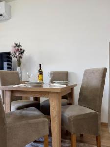 a dining room table with two chairs and a bottle of wine at Apartman Kitanović 1 Vrnjačka Banja in Ruđinci +13 photos