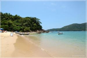 a beach with boats in the water and people on it at Casa na Mata - 2 min da Praia de fora com WiFi in Paraty