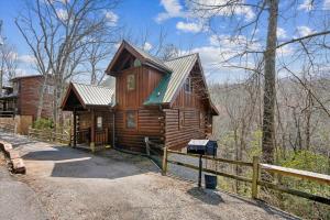 a wooden cabin in the woods with a fence at Beary Cozy Cabin by Venture Smoky Mountains in Sevierville