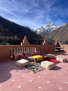 a patio with pillows and a table with mountains in the background at Atlas Green Lodge in Imlil +18 photos