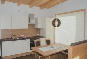 eine Küche mit weißen Schränken und einem Holztisch in der Unterkunft Apart Kaunergrat in Kauns
