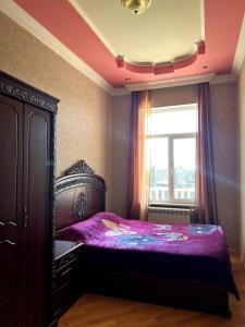 a bedroom with a bed with purple sheets and a window at Fireside Fiesta Haven in Maglaki