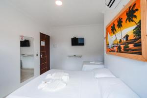 a bedroom with a white bed and a painting on the wall at Pousada La Belle in Maragogi