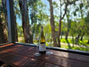 a bottle of wine and two glasses on a wooden table at Bridgewater Caravan Park Near Bendigo in Bridgewater-on-Loddon
