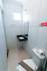 a white bathroom with a toilet and a sink at Pousada La Belle in Maragogi