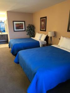 a hotel room with three beds with blue sheets at Lakeview Resort Motel in Wasaga Beach +58 photos