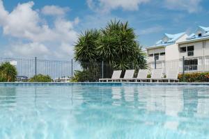 a swimming pool with chairs and a building at Appartement Reflets Marins in Saint Martin