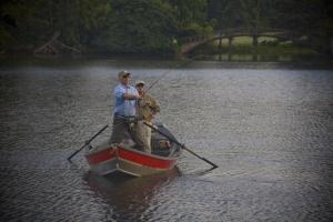 two men and a dog in a boat in the water at Callaway Resort & Gardens in Pine Mountain
