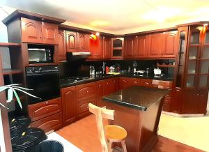 a kitchen with wooden cabinets and black appliances at Hostal SAVEVA in Medellín +9 photos